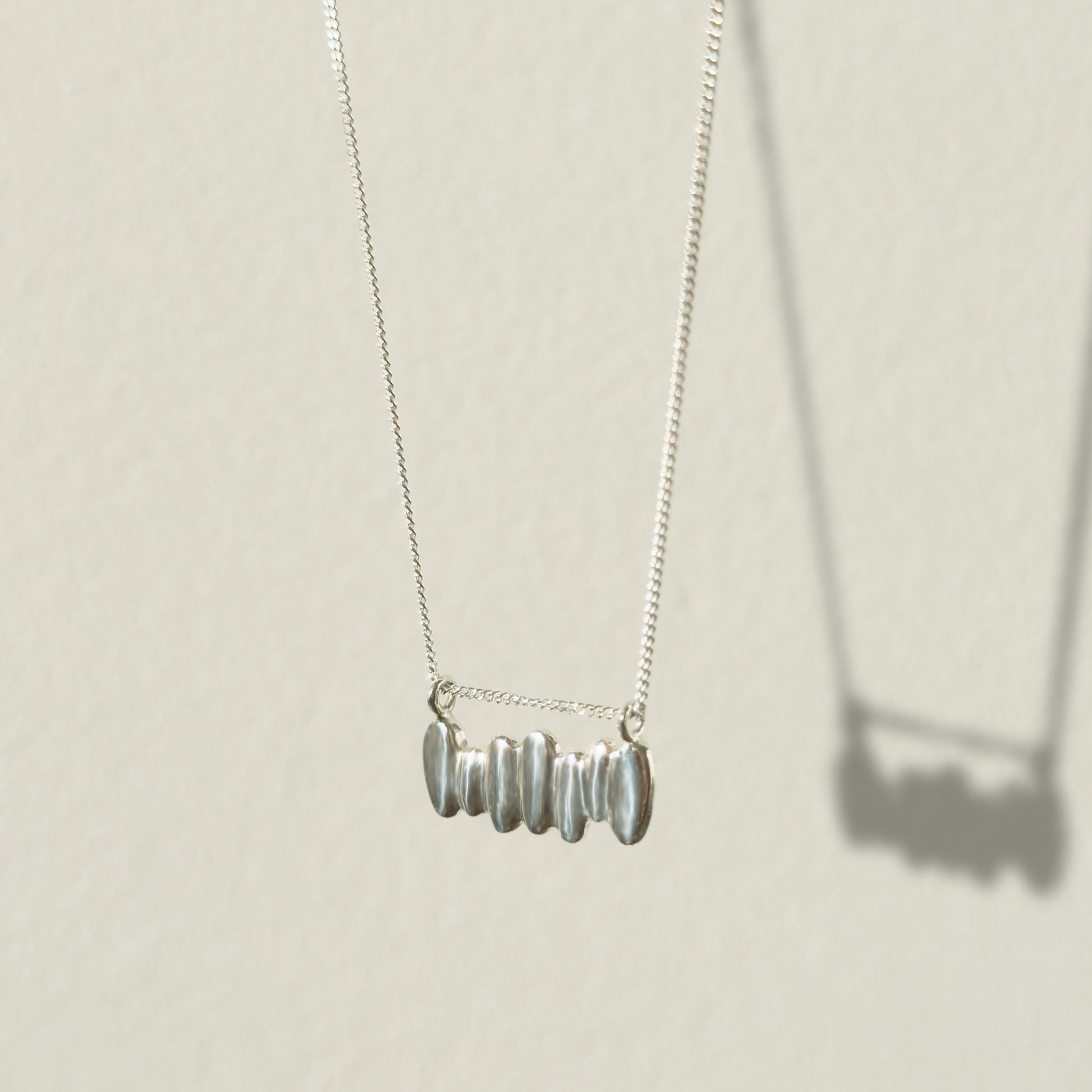 Angled front view of the Meridian textured silver necklace, pictured on a light plain background.