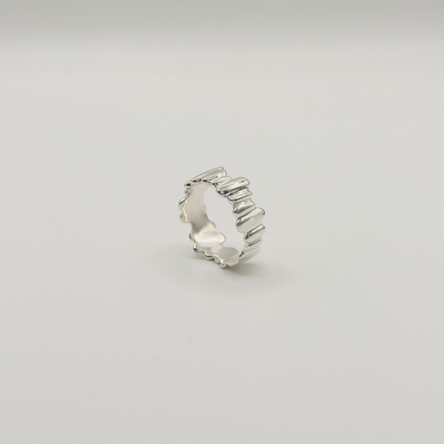 Angled side view of the Meridian textured silver ring, pictured on a light plain background.