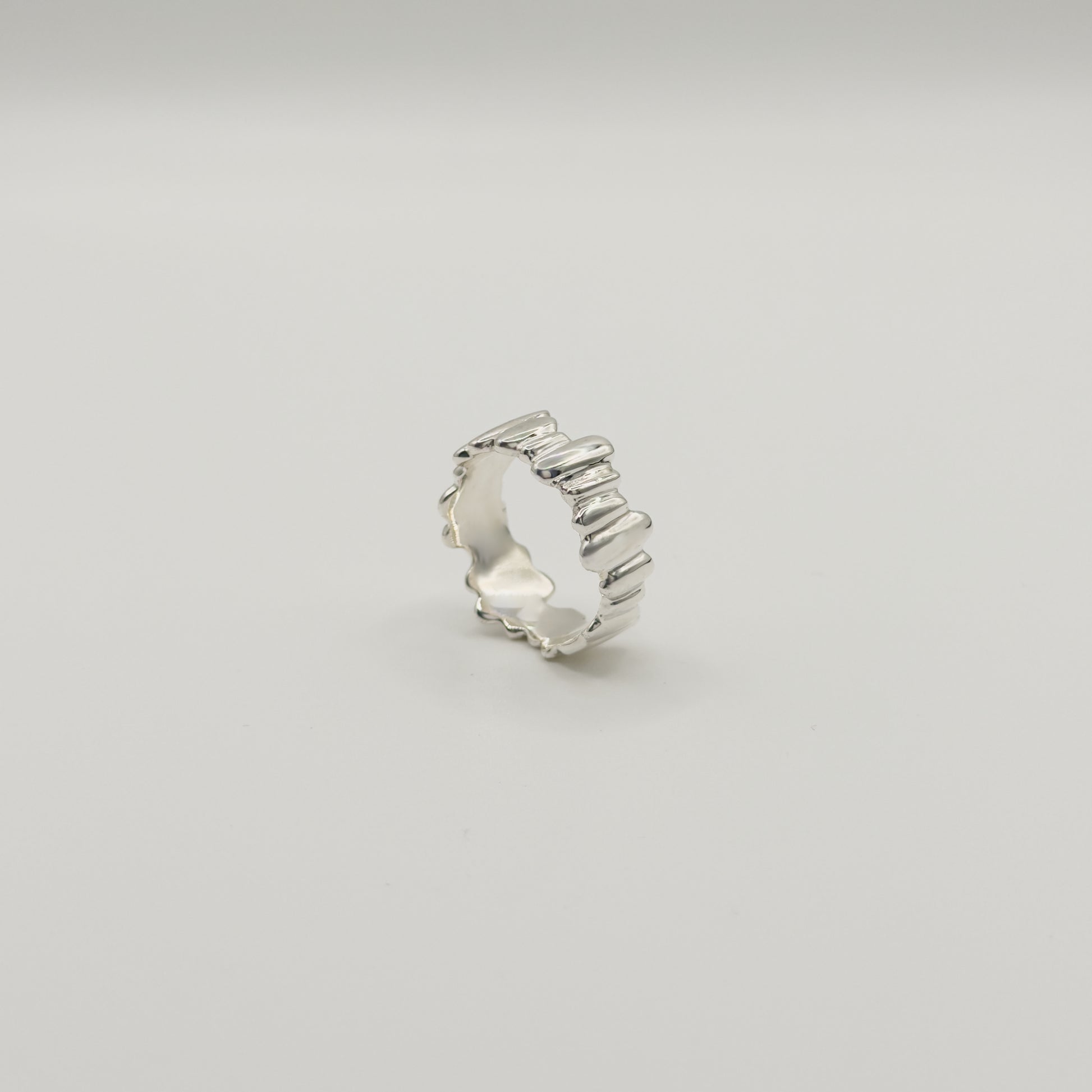 Angled side view of the Meridian textured silver ring, pictured on a light plain background.
