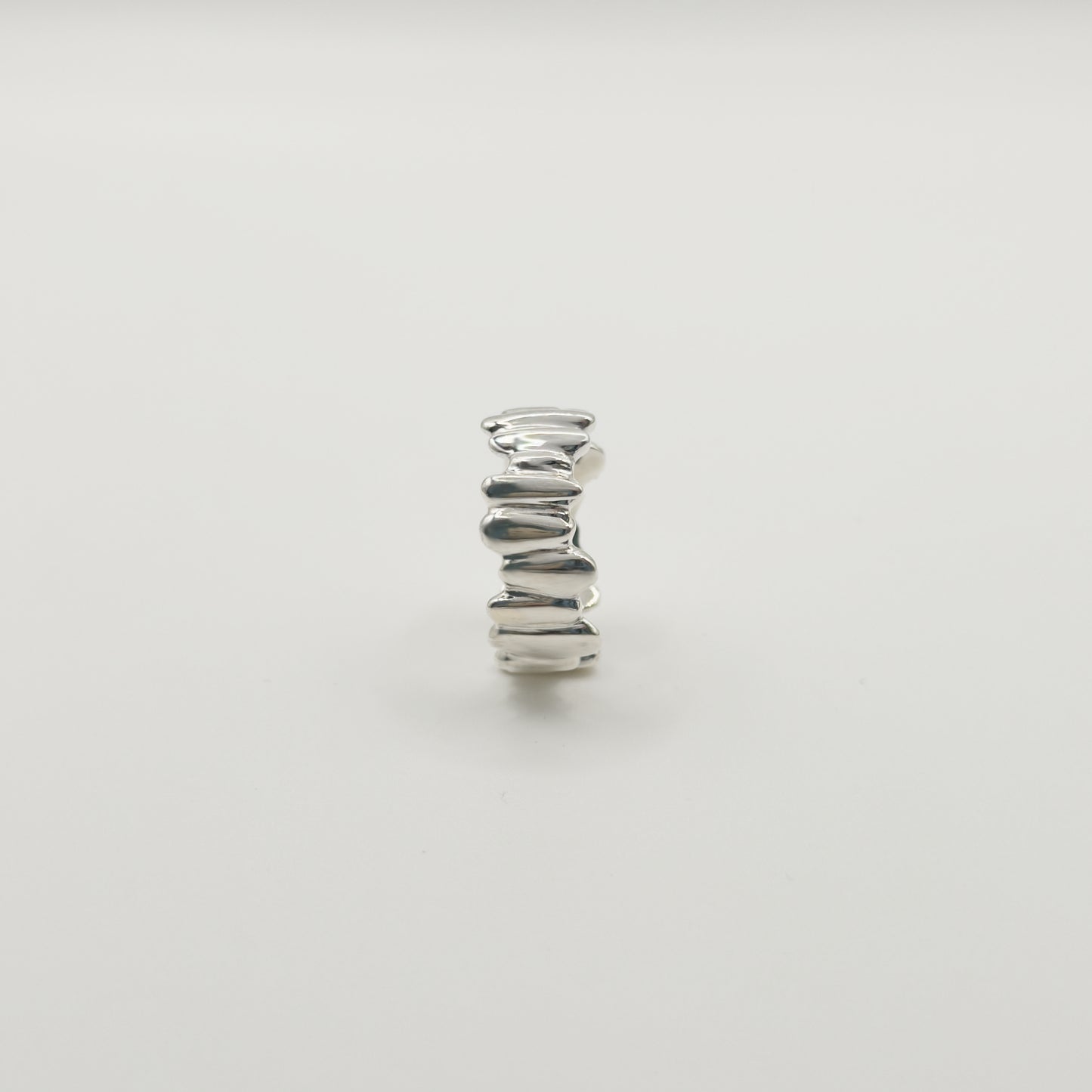 Side view of the Meridian textured silver ring, pictured on a light plain background.