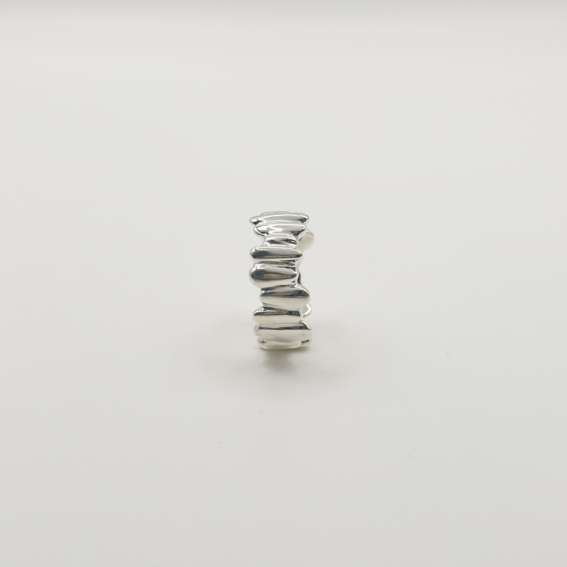 Side view of the Meridian textured silver ring, pictured on a light plain background.
