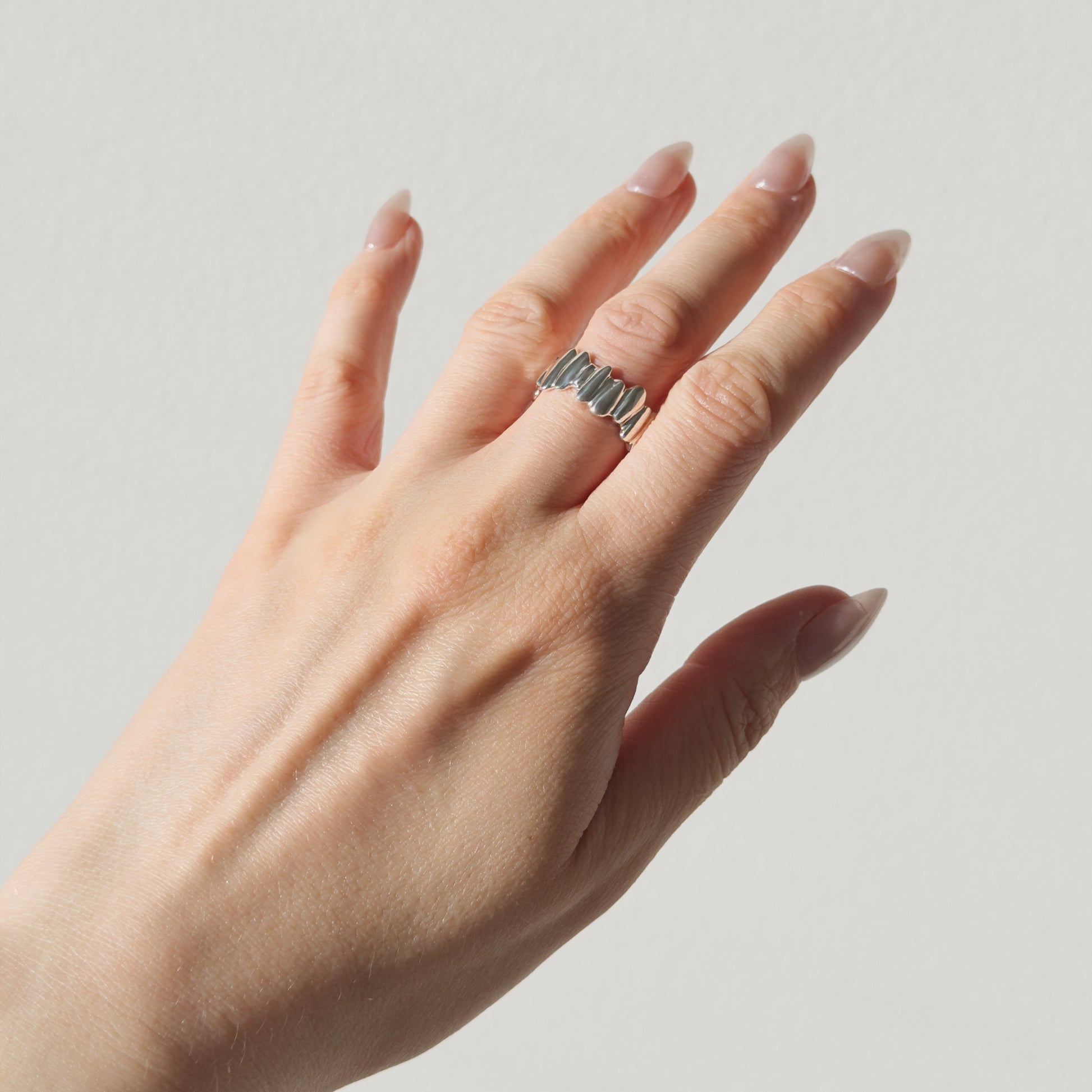 Hand wearing the Meridian textured silver ring on a plain background.