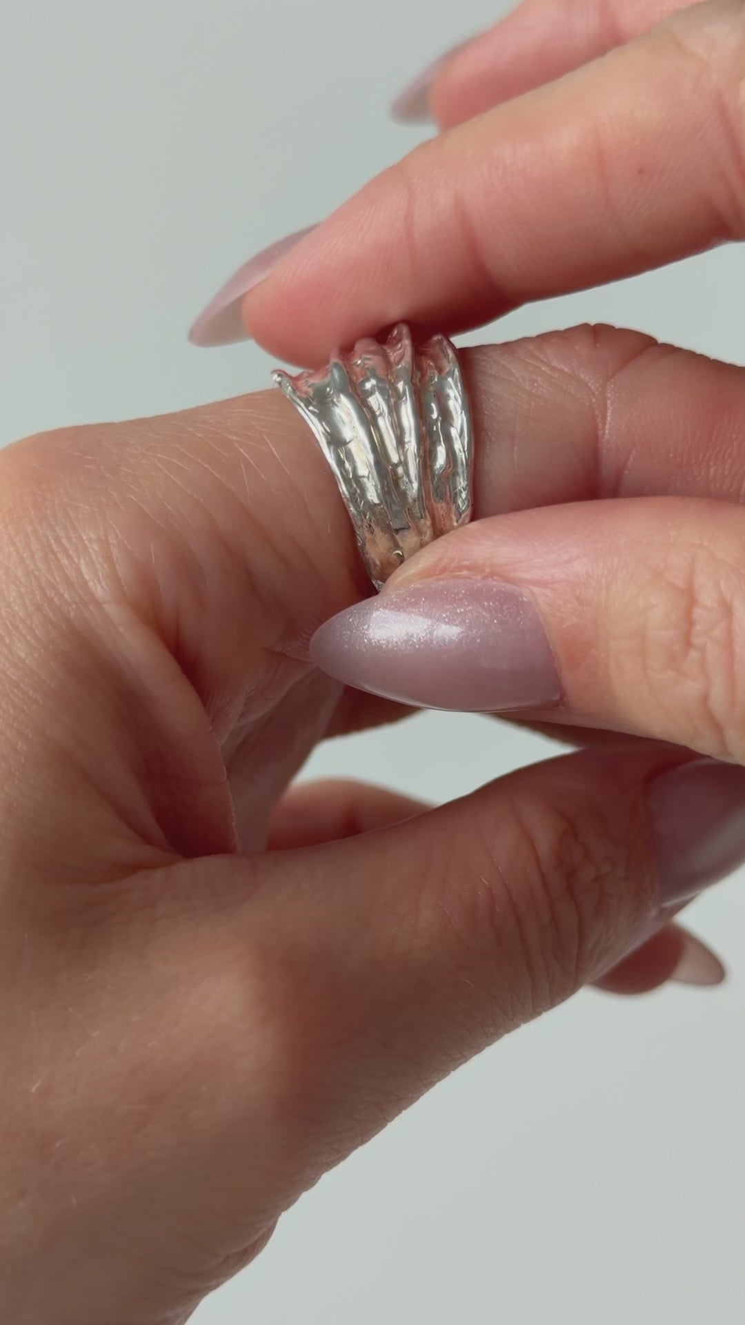 A close up of a hand feeling the texture of the Canyon ring. Pictured on a light background.