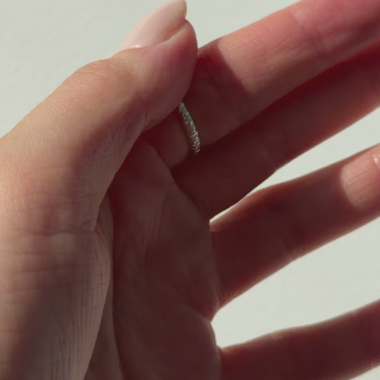 A close up of a hand feeling the texture of the Echo ring. Pictured on a light background.