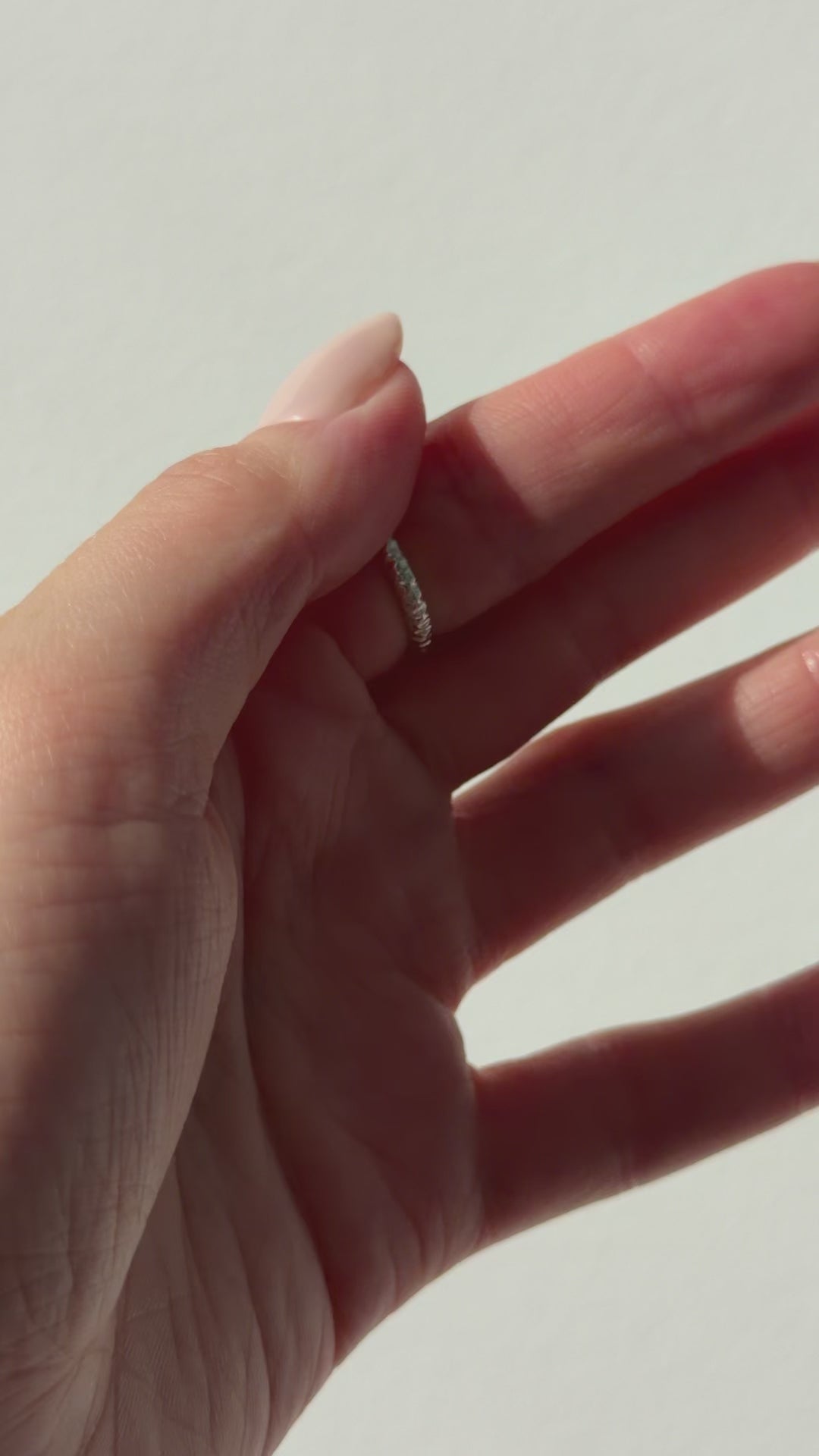 A close up of a hand feeling the texture of the Echo ring. Pictured on a light background.