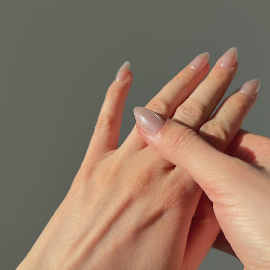 A close up of a hand feeling the texture of the Atoll ring. Pictured on a light gray background.