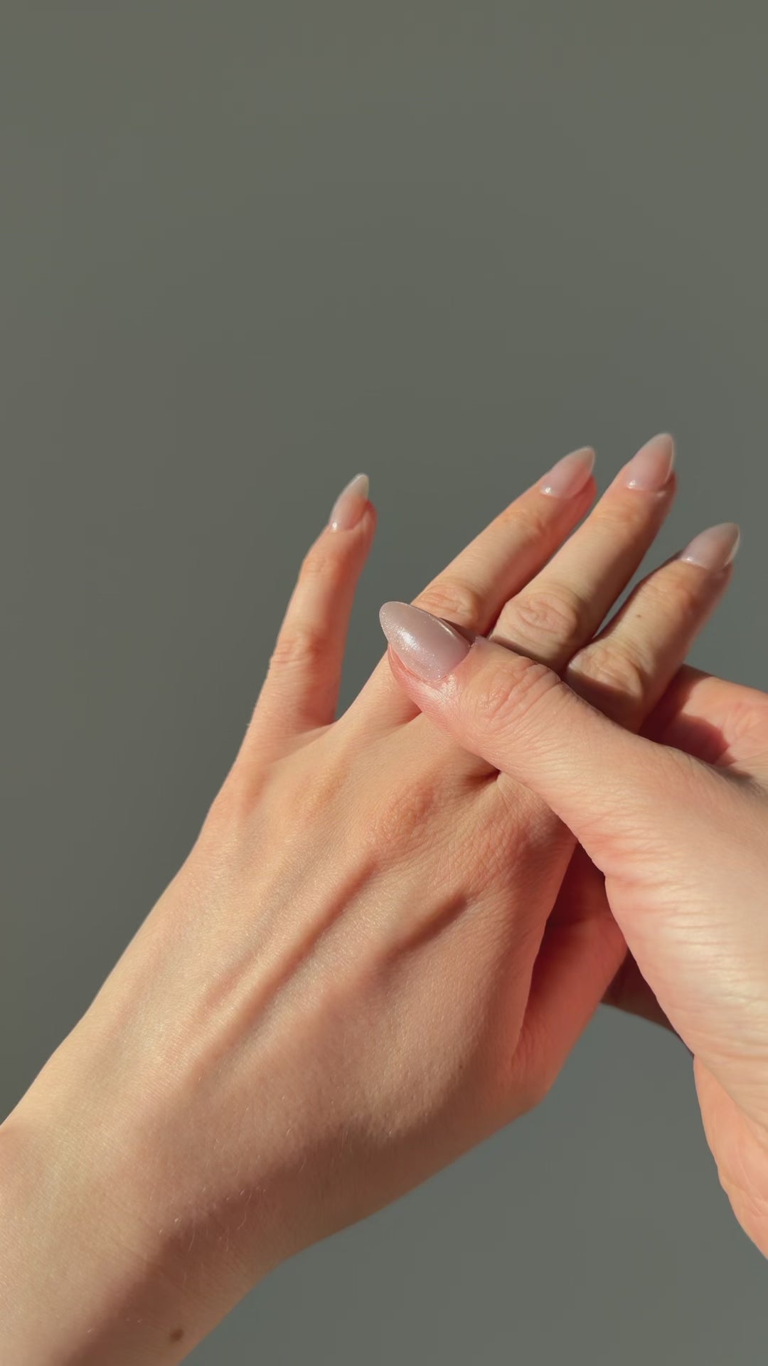 A close up of a hand feeling the texture of the Atoll ring. Pictured on a light gray background.