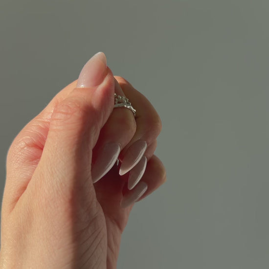 A close up of a hand feeling the texture of the Sequence ring. Pictured on a light gray background.