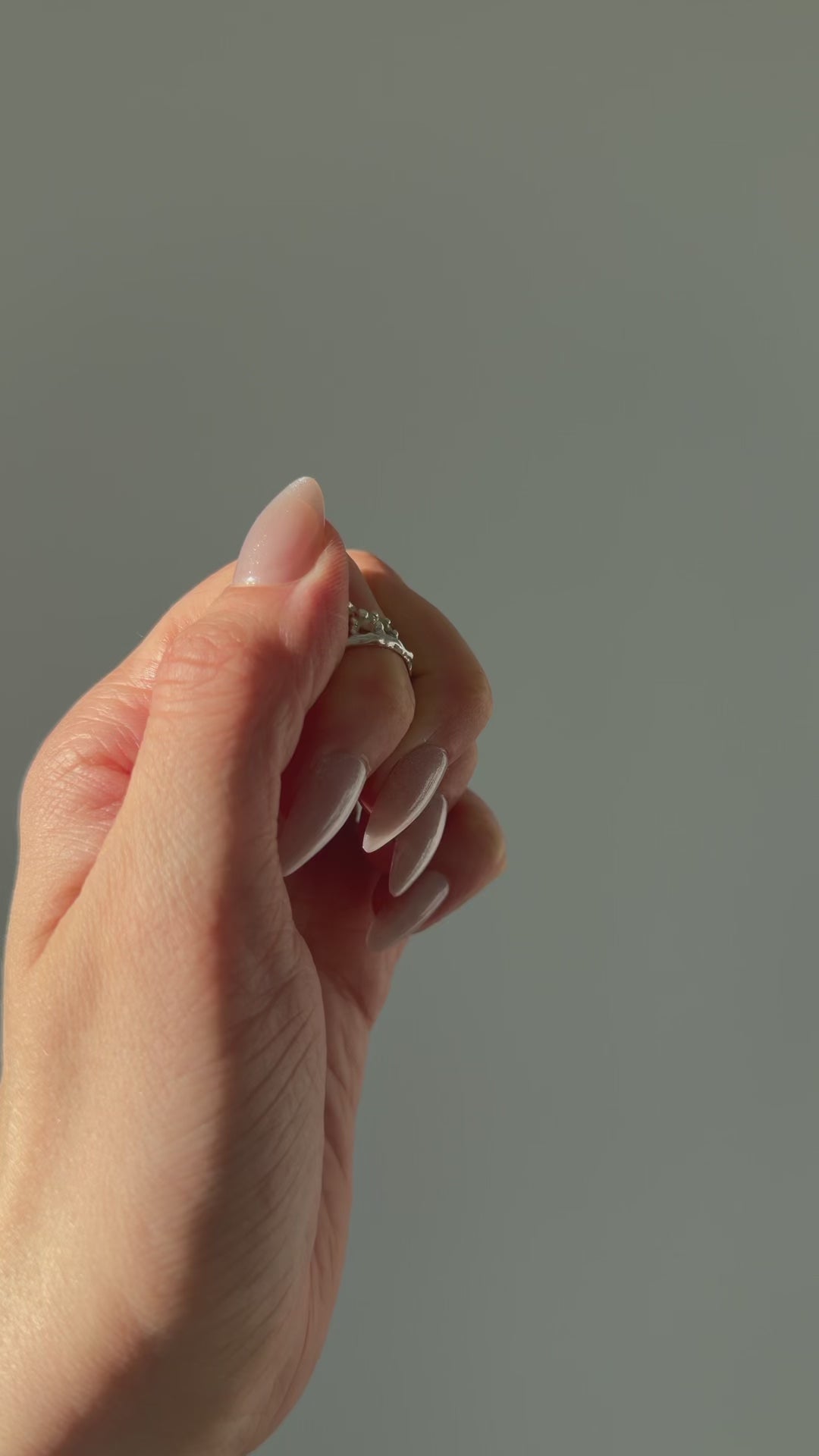 A close up of a hand feeling the texture of the Sequence ring. Pictured on a light gray background.