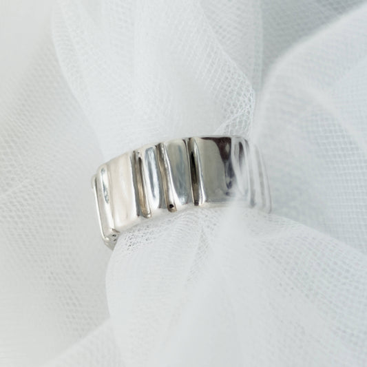 Front view of the Ripple silver ring, pictured on a light textured background.