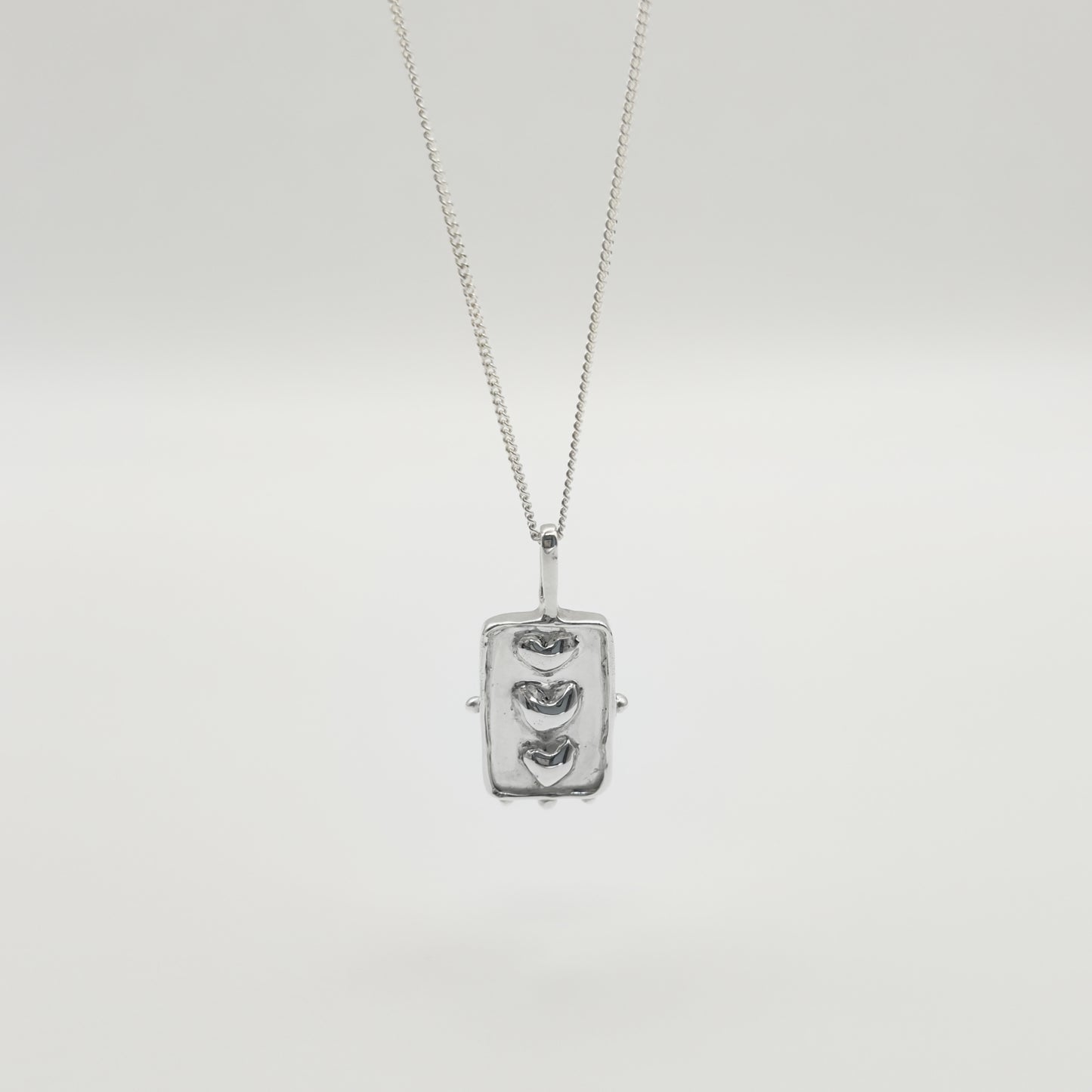 Front view of the Self-Compassion textured silver pendant on a curb chain, pictured on a light plain background.