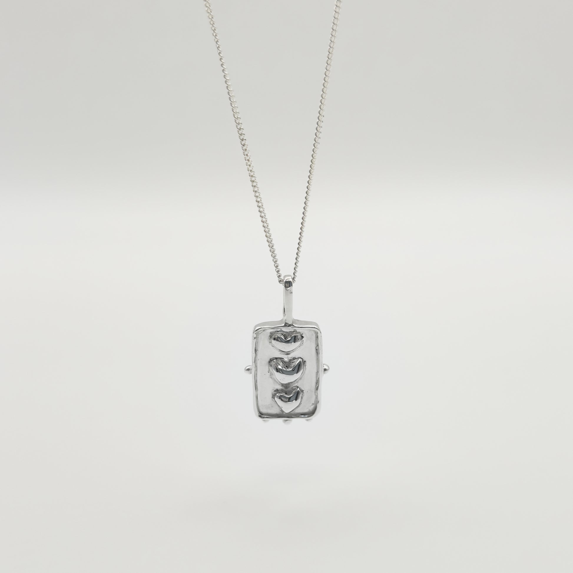 Front view of the Self-Compassion textured silver pendant on a curb chain, pictured on a light plain background.
