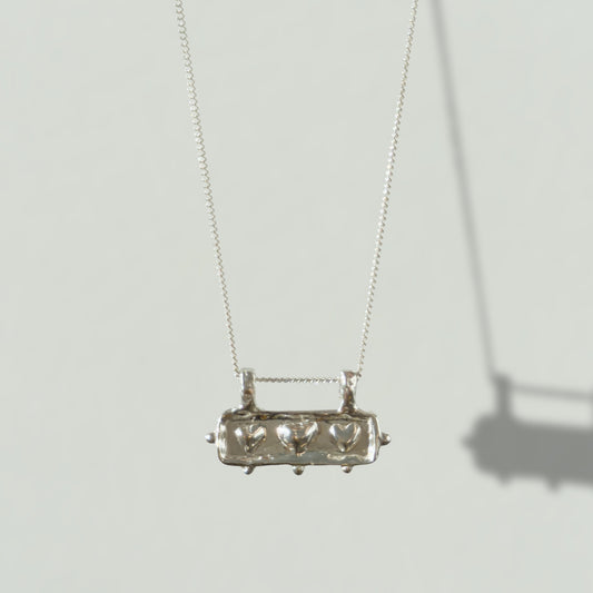 Front view of the Self-Love textured silver pendant on a curb chain, pictured on a light plain background.
