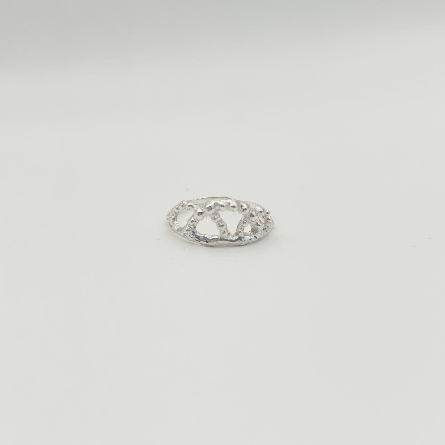 Front view of the Sequence textured silver ring, pictured on a light plain background.
