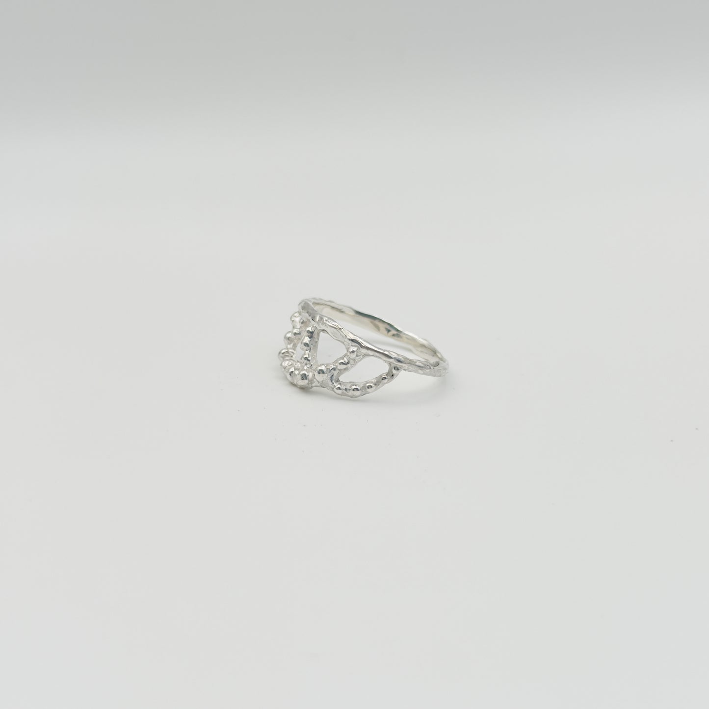 Angled front view of the Sequence textured silver ring, pictured on a light plain background.