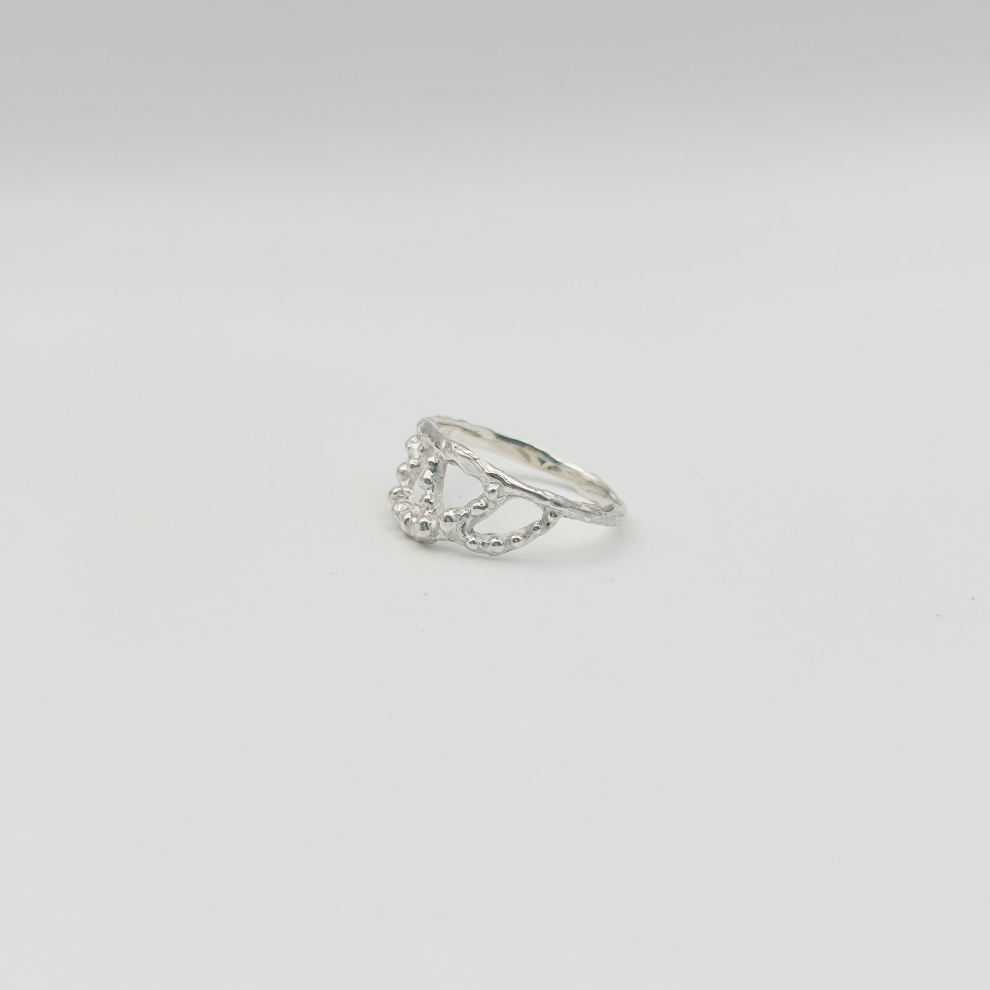 Angled front view of the Sequence textured silver ring, pictured on a light plain background.