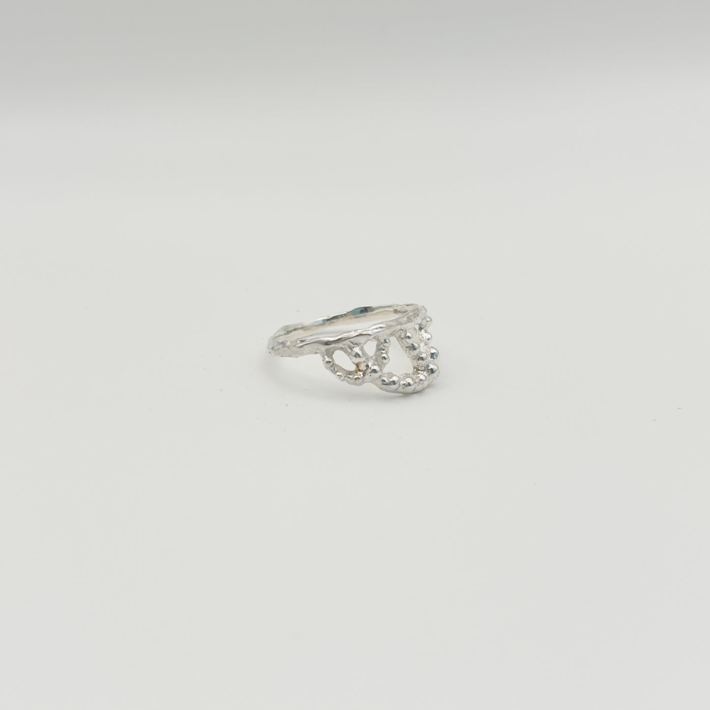 Angled front view of the Sequence textured silver ring, pictured on a light plain background.