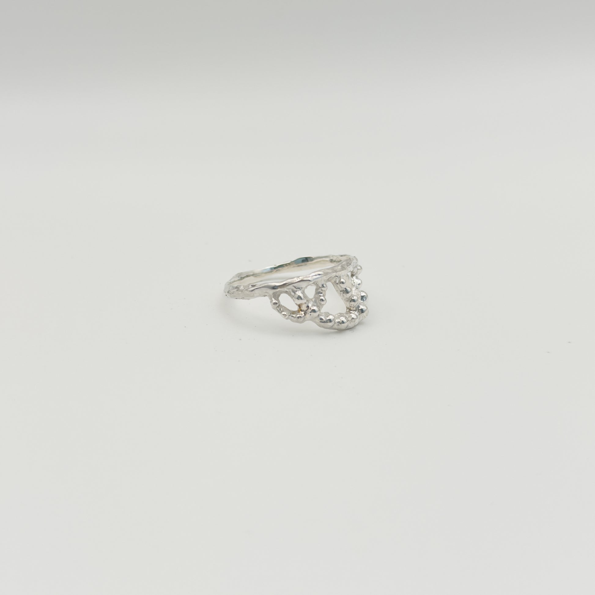 Angled front view of the Sequence textured silver ring, pictured on a light plain background.