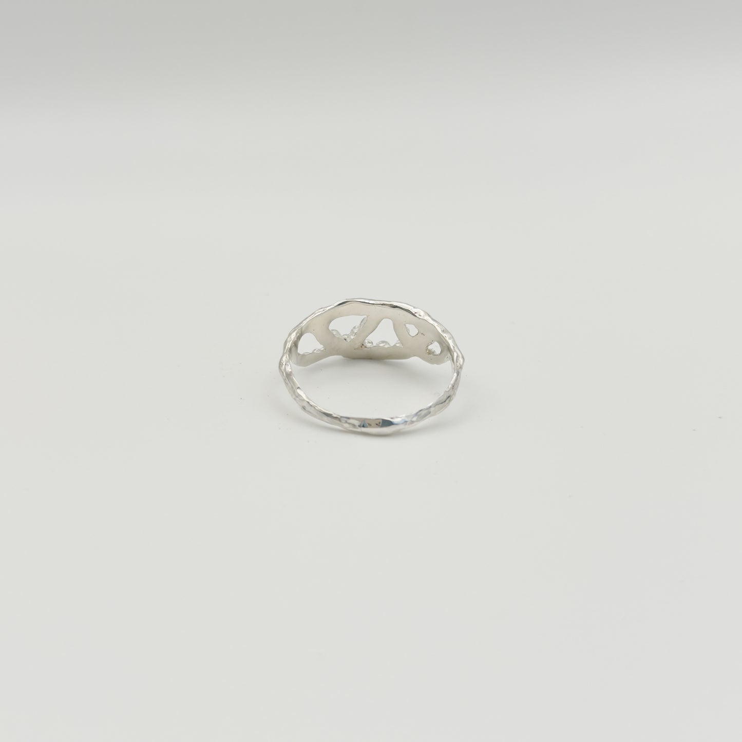Back view of the Sequence textured silver ring, pictured on a light plain background.