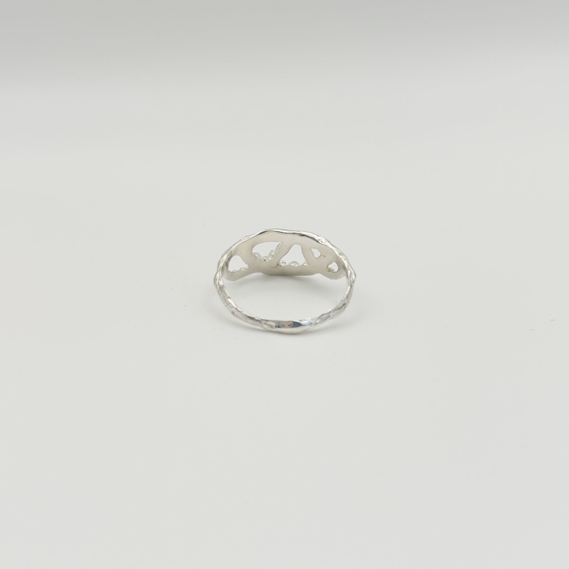 Back view of the Sequence textured silver ring, pictured on a light plain background.