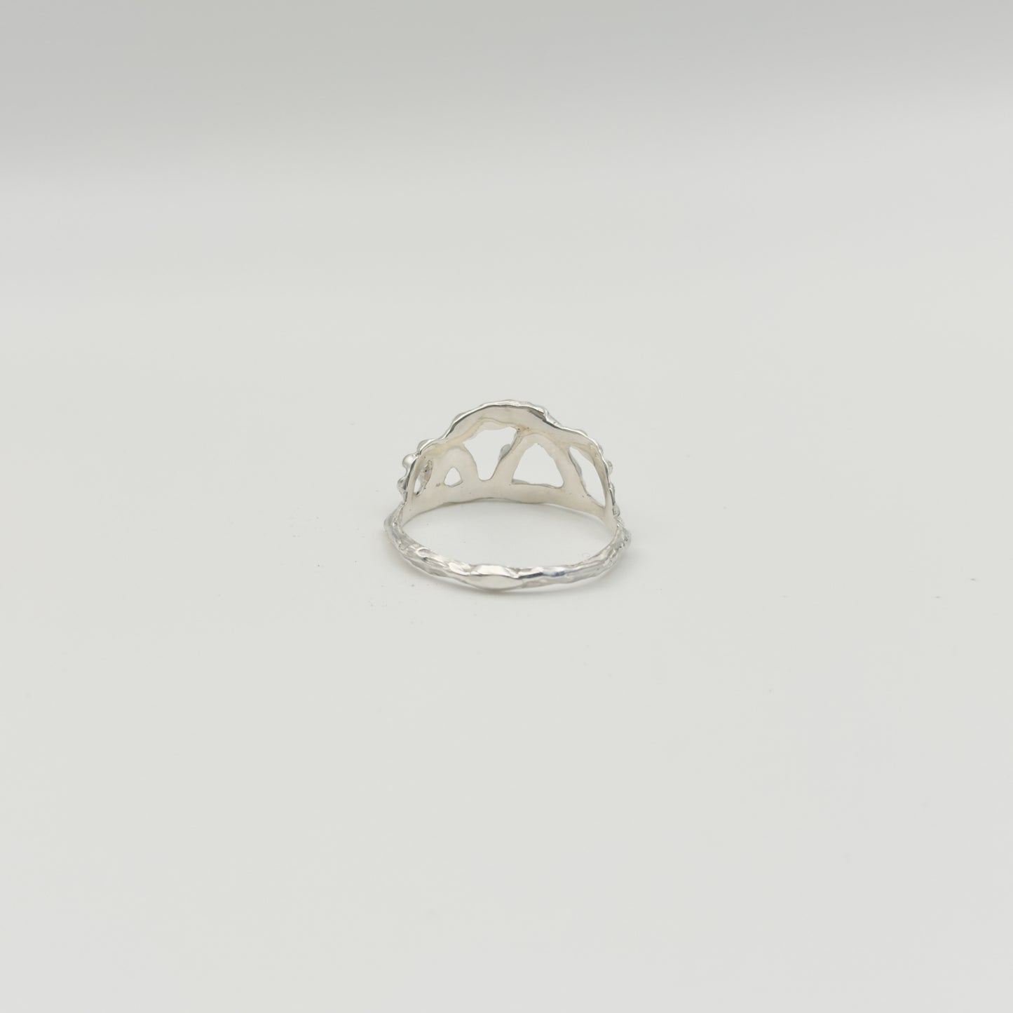 Back view of the Sequence textured silver ring, pictured on a light plain background.