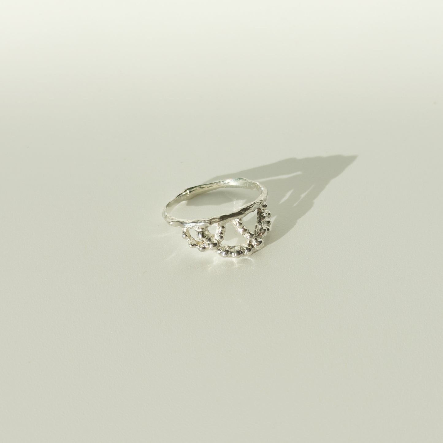 Angled front view of the Sequence textured silver ring, pictured on a light plain background.