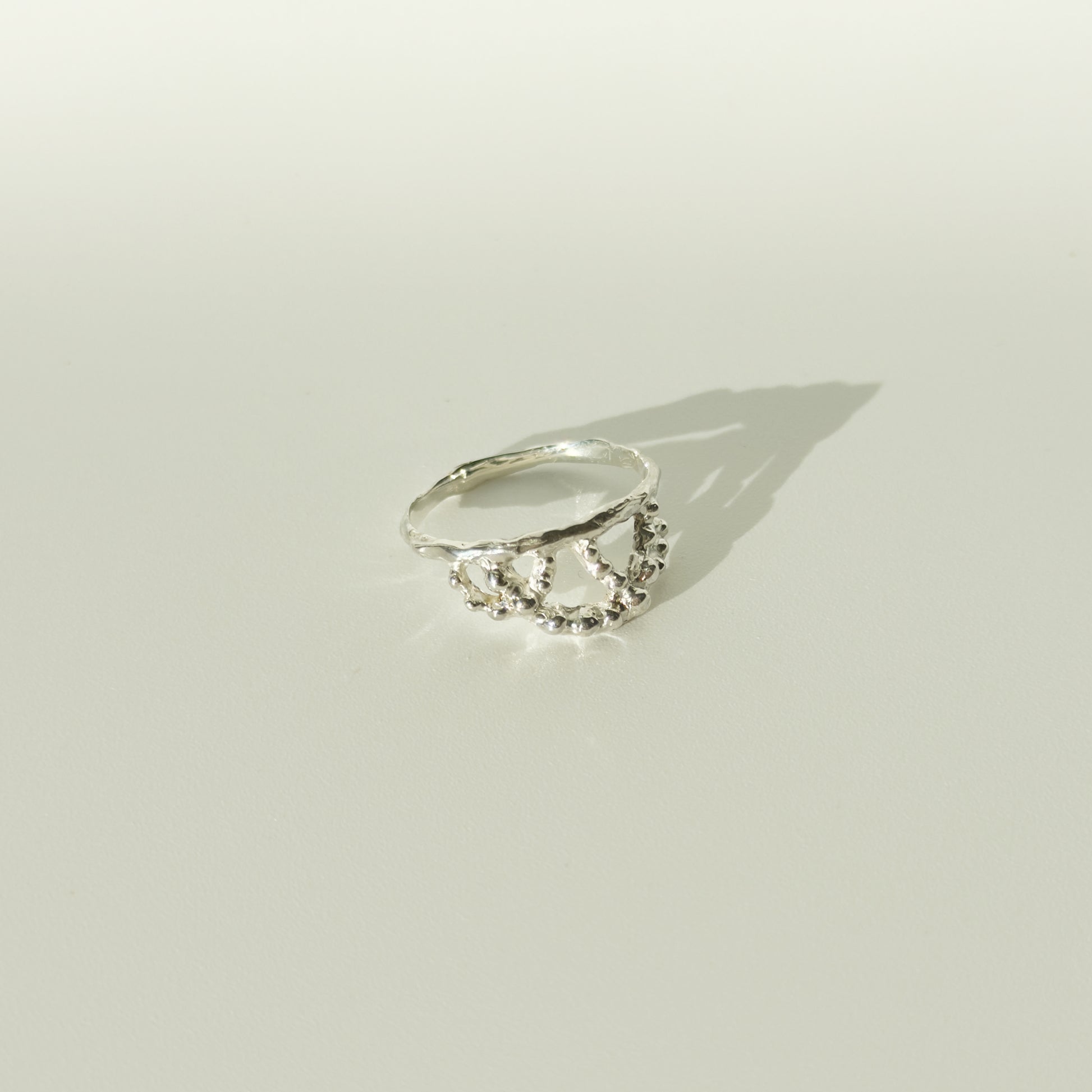 Angled front view of the Sequence textured silver ring, pictured on a light plain background.