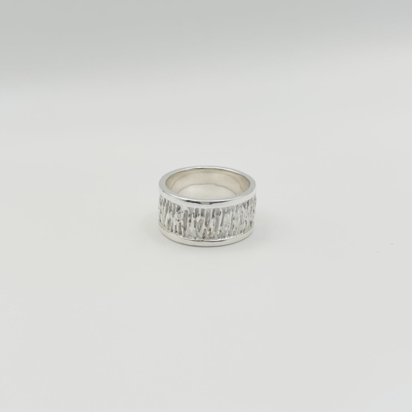 Back view of the Solace textured silver ring, pictured on a light plain background.