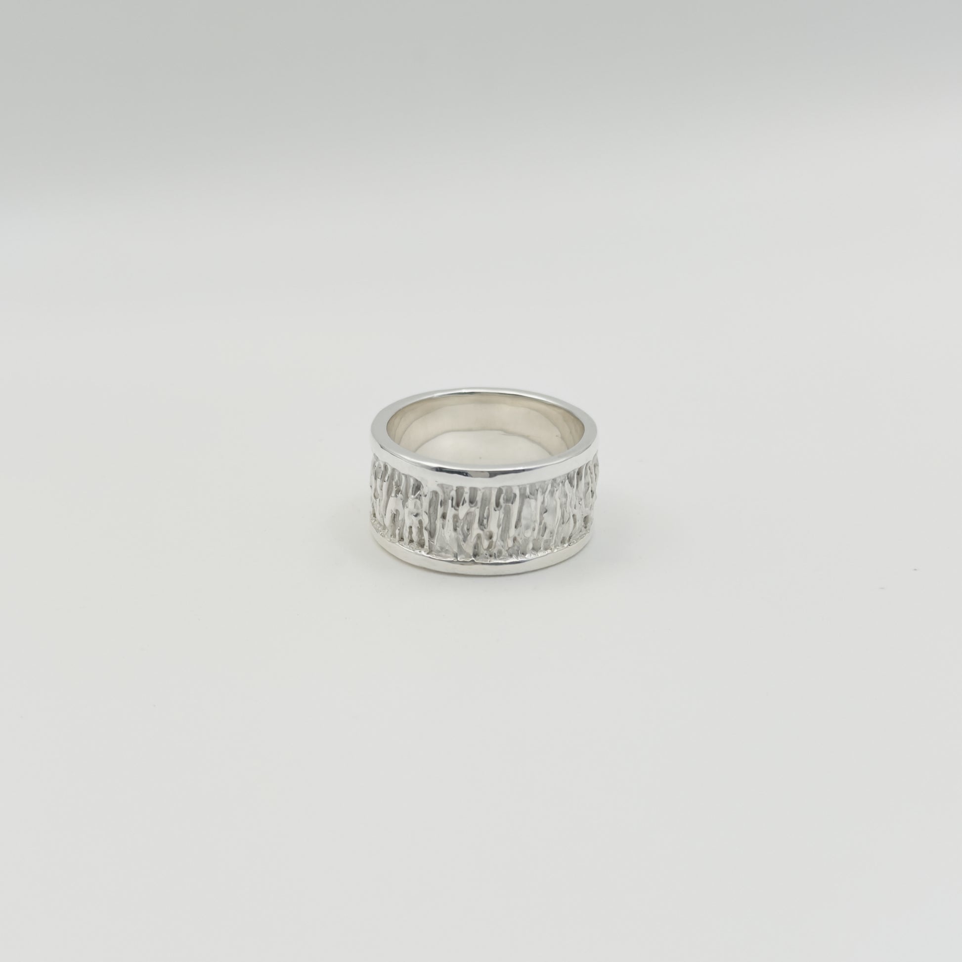 Back view of the Solace textured silver ring, pictured on a light plain background.