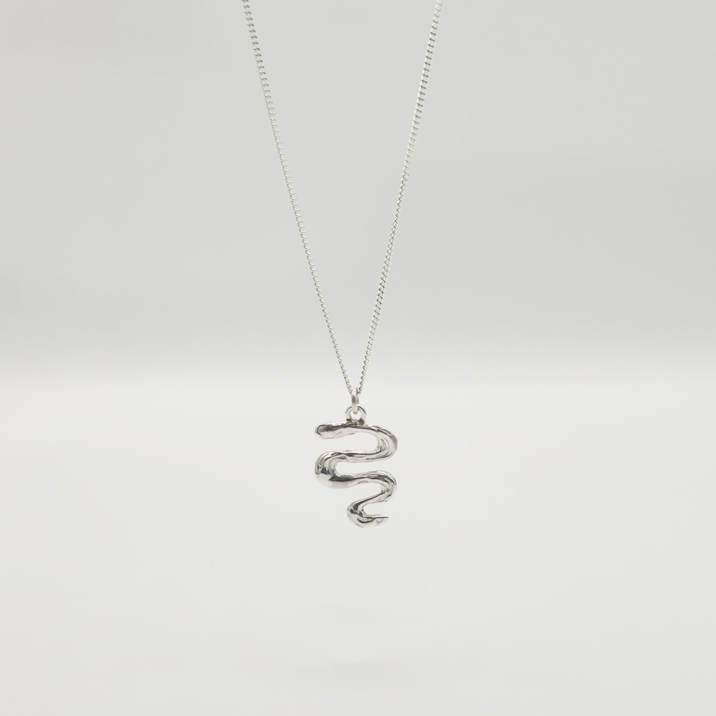 Front view of the Unfold textured silver necklace, pictured on a light plain background.