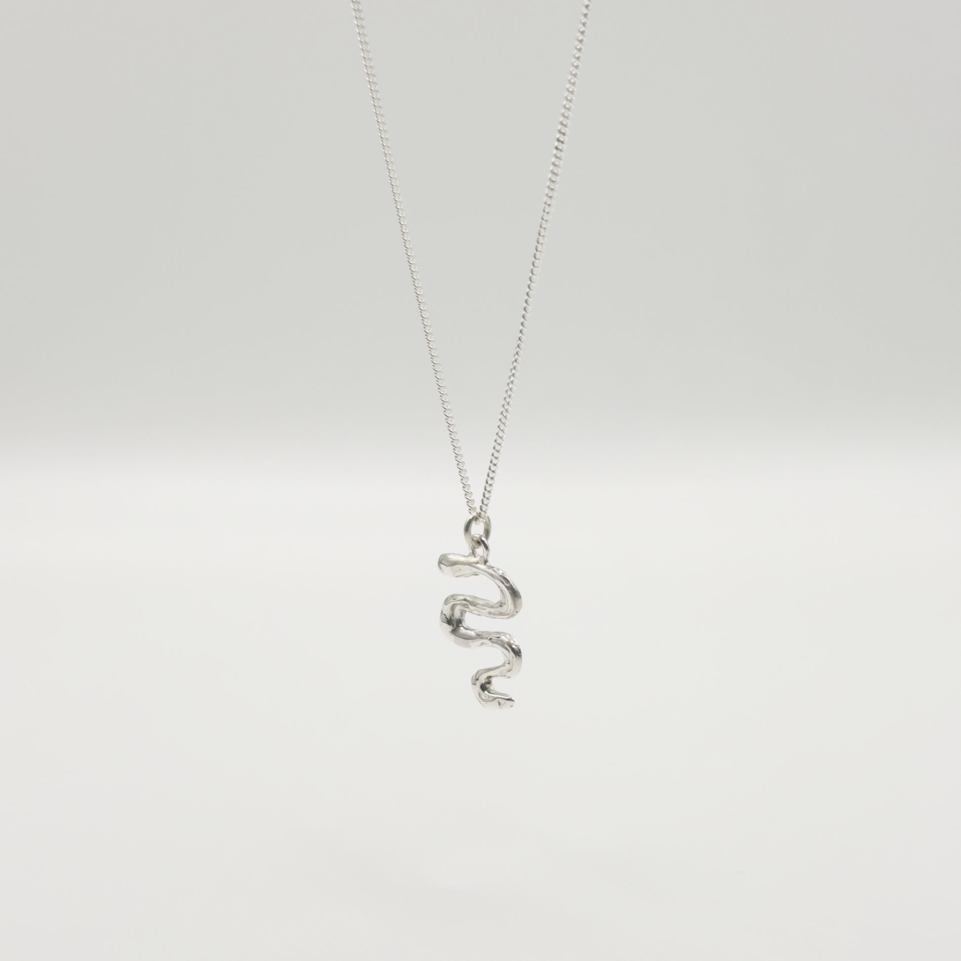 Angled front view of the Unfold textured silver necklace, pictured on a light plain background.