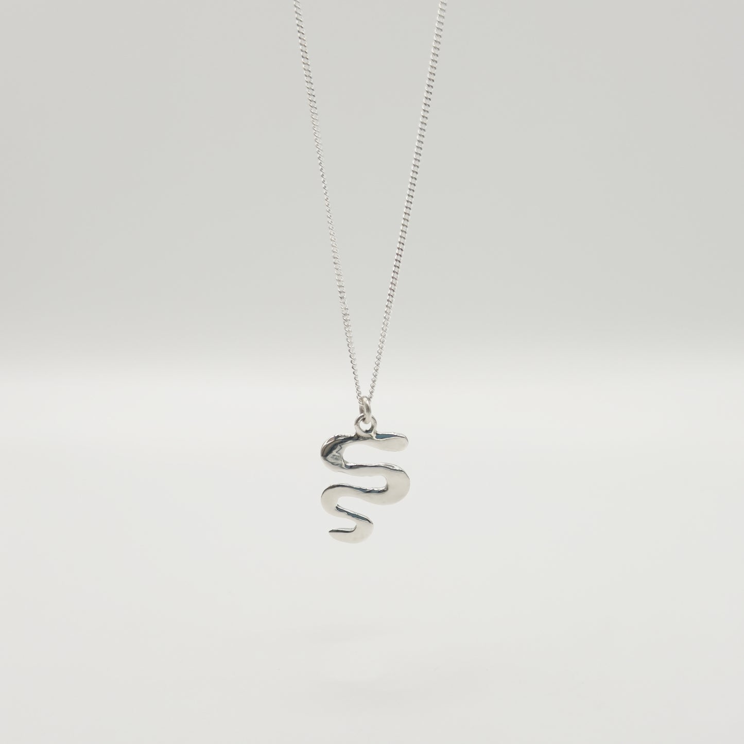 Back view of the Unfold textured silver necklace, pictured on a light plain background.