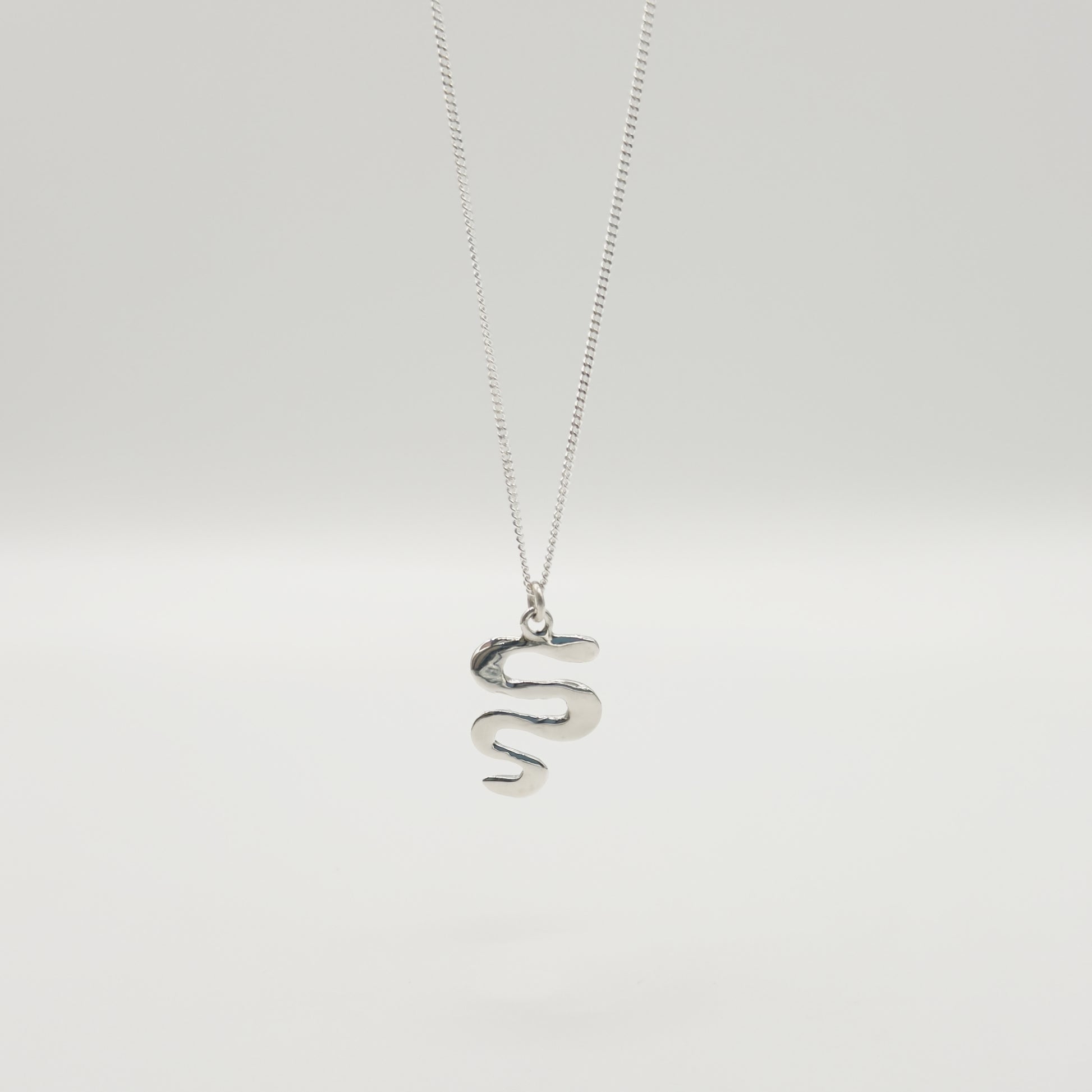 Back view of the Unfold textured silver necklace, pictured on a light plain background.