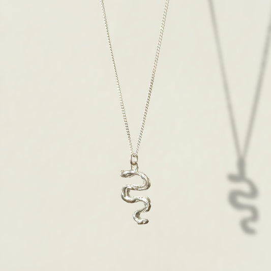 Angled front view of the Unfold textured silver necklace, pictured on a light plain background.