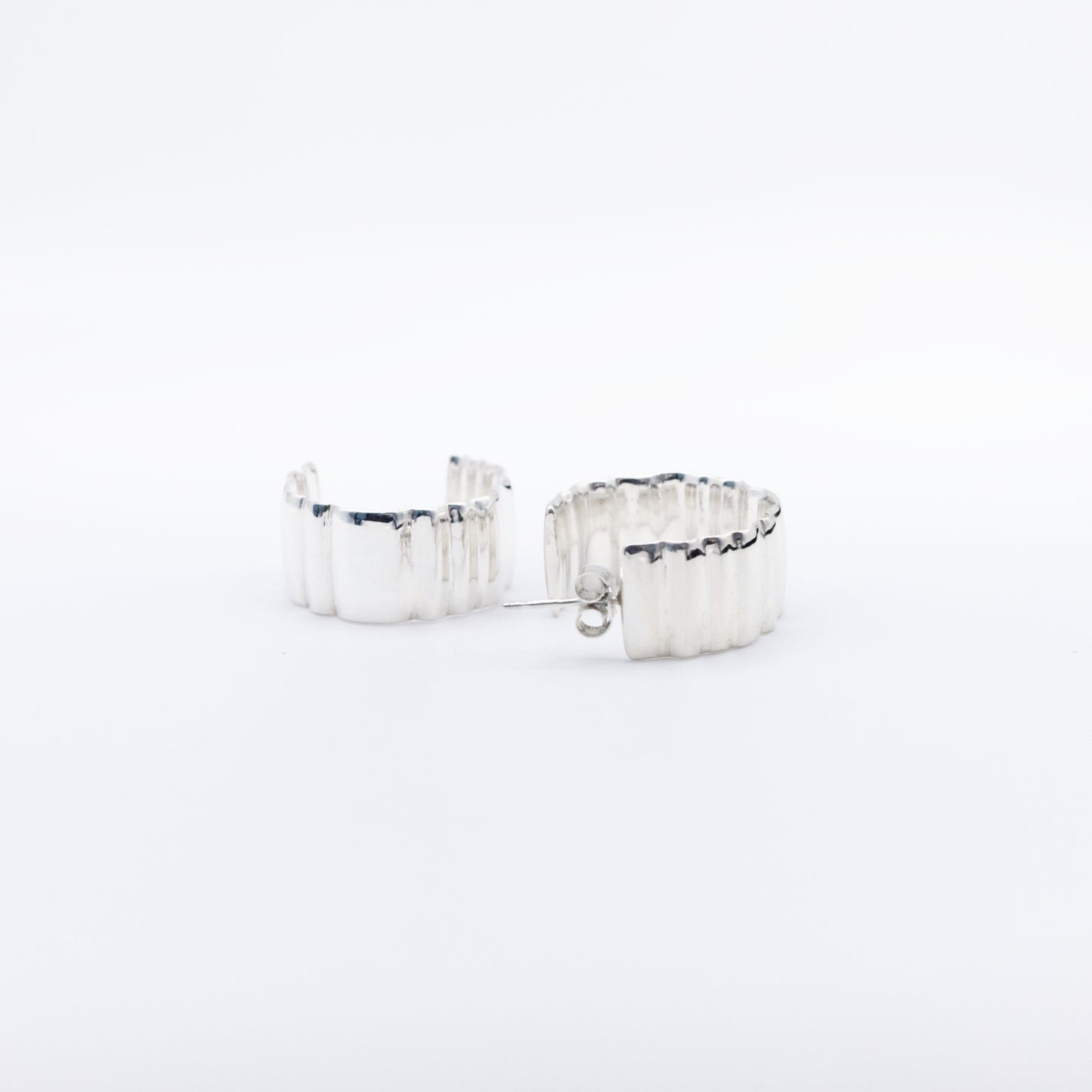 A pair of Wave Large silver hoop earrings, front and back views, pictured on a light plain background.