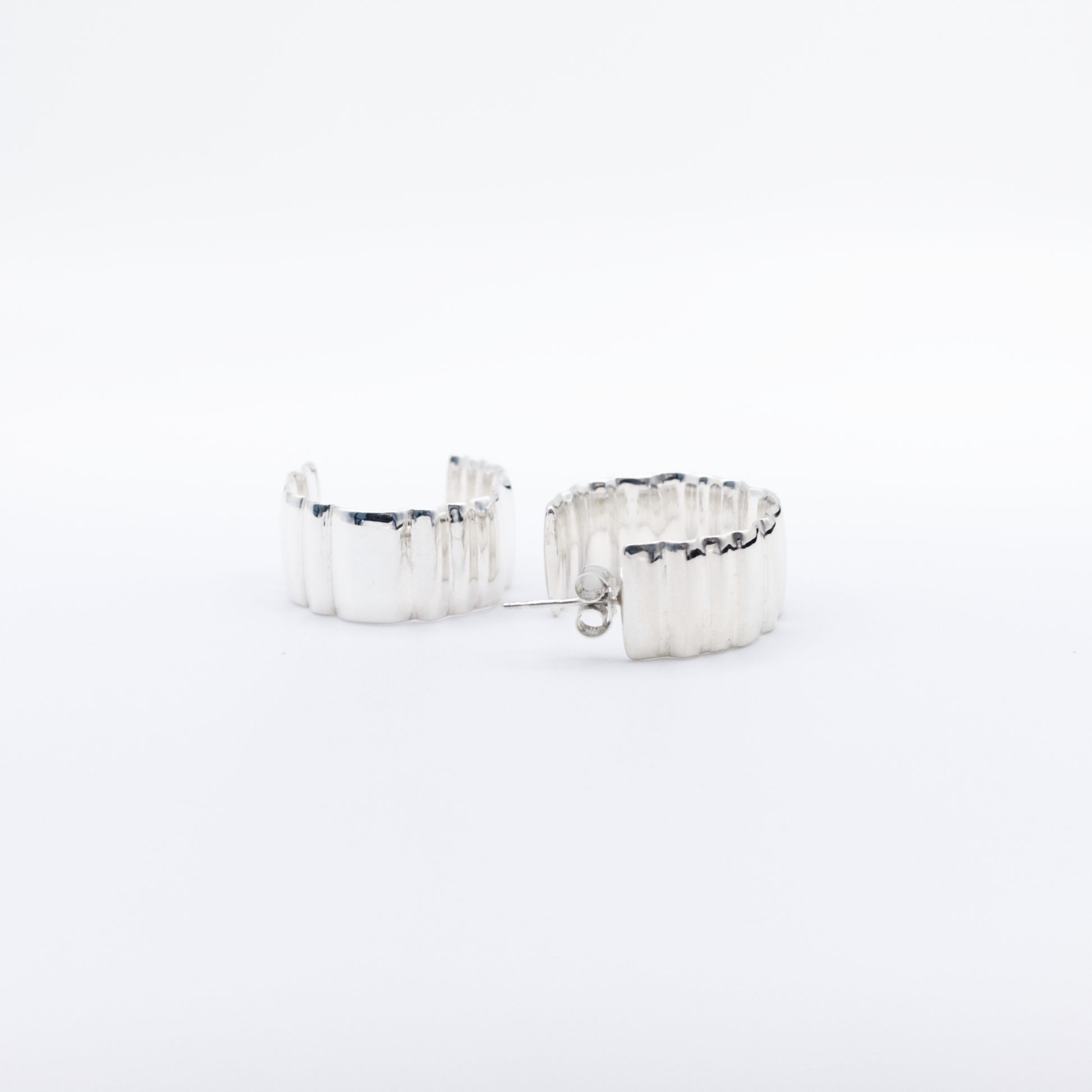 A pair of Wave Large silver hoop earrings, front and back views, pictured on a light plain background.