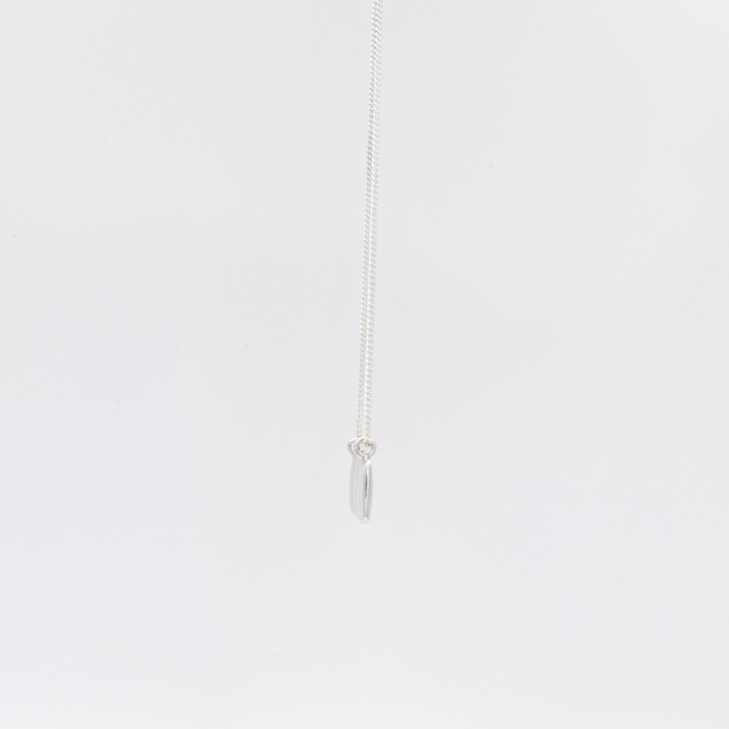 Side view of the Wave silver necklace with a textured rectangular pendant, pictured on a light plain background.