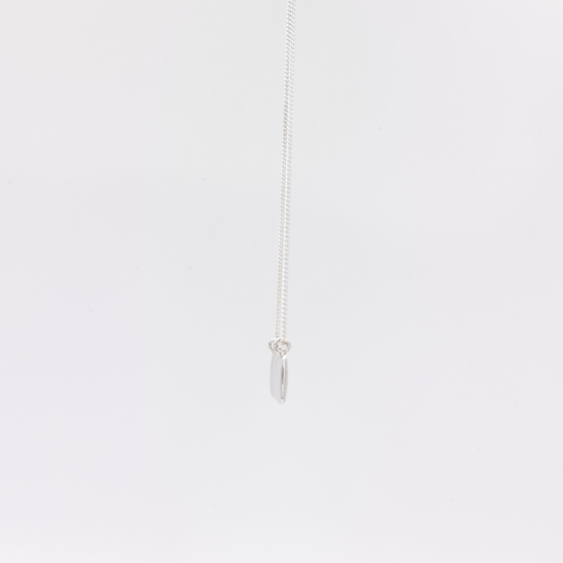Side view of the Wave silver necklace with a textured rectangular pendant, pictured on a light plain background.