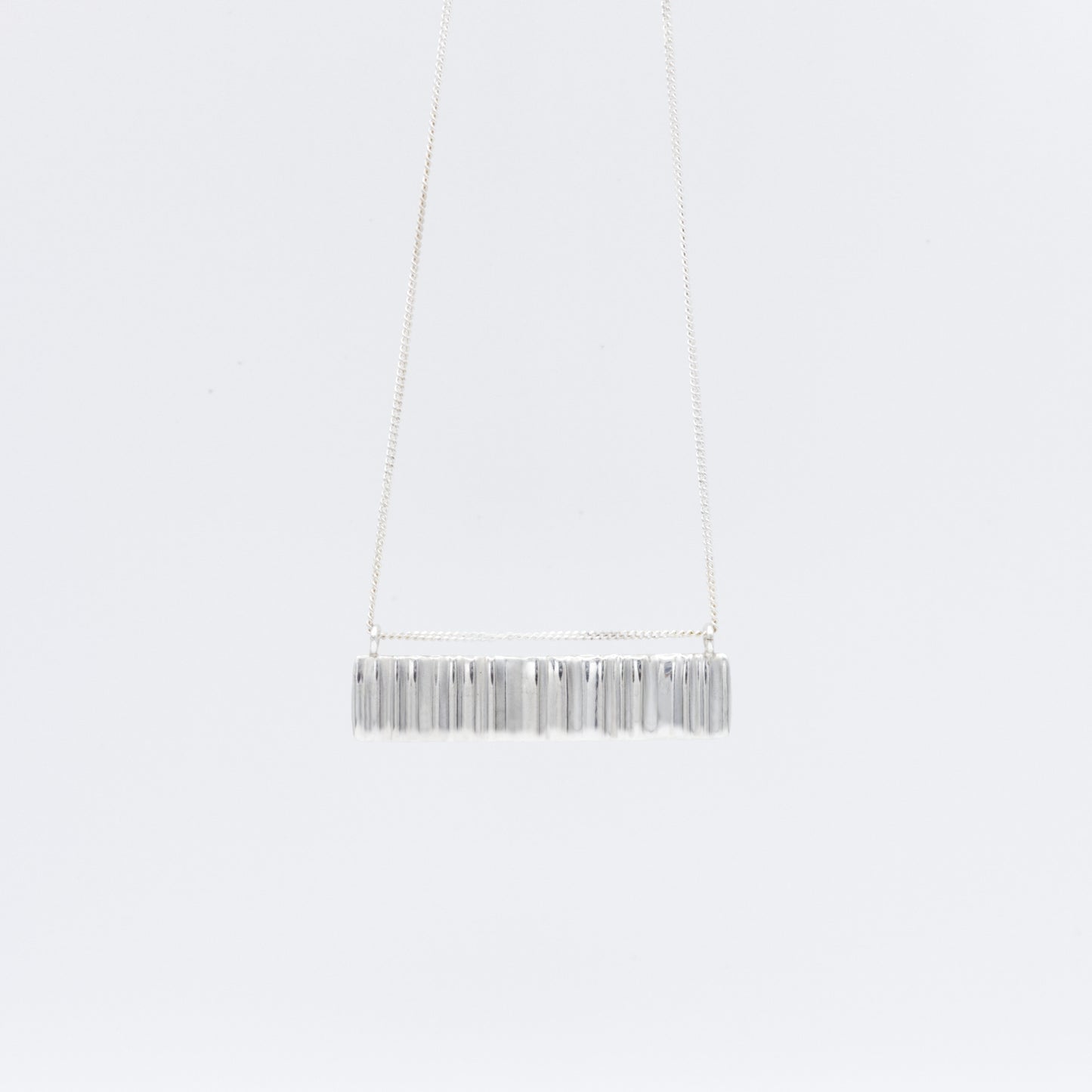 Front view of the Wave silver necklace with a textured rectangular pendant, pictured on a light plain background.