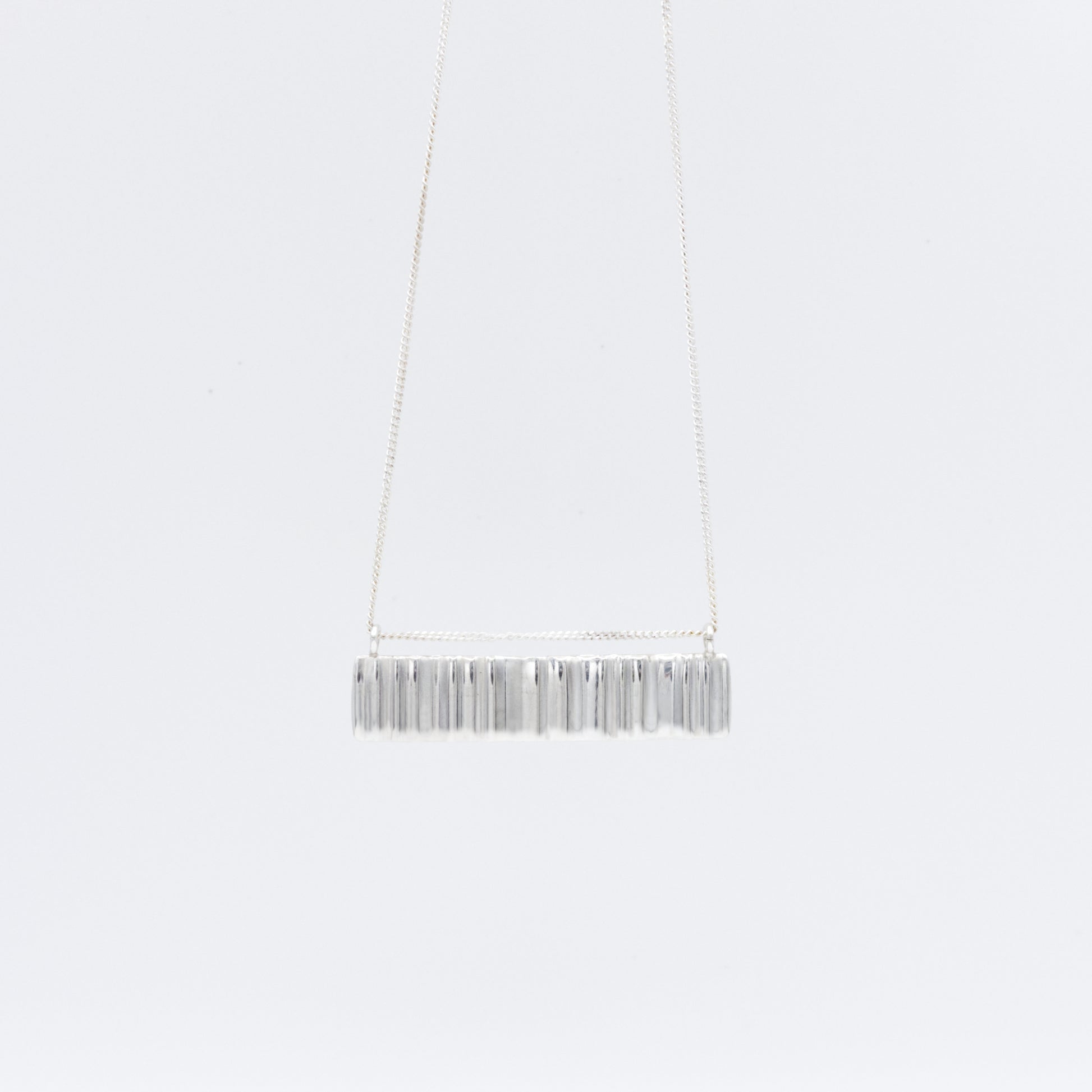 Front view of the Wave silver necklace with a textured rectangular pendant, pictured on a light plain background.