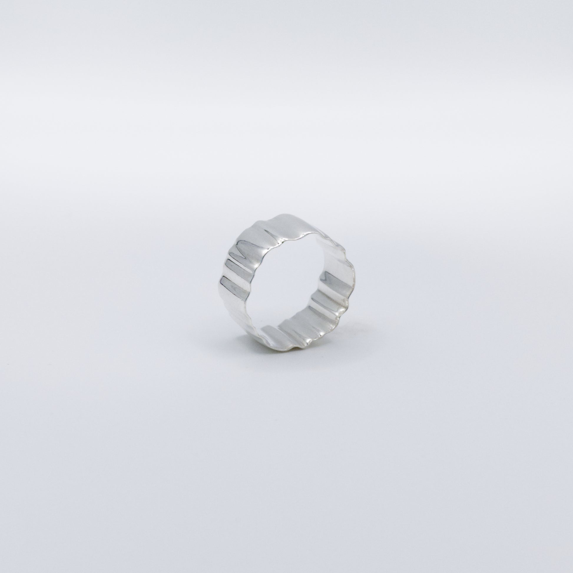 Angled side view of the Wave silver ring, pictured on a light plain background.