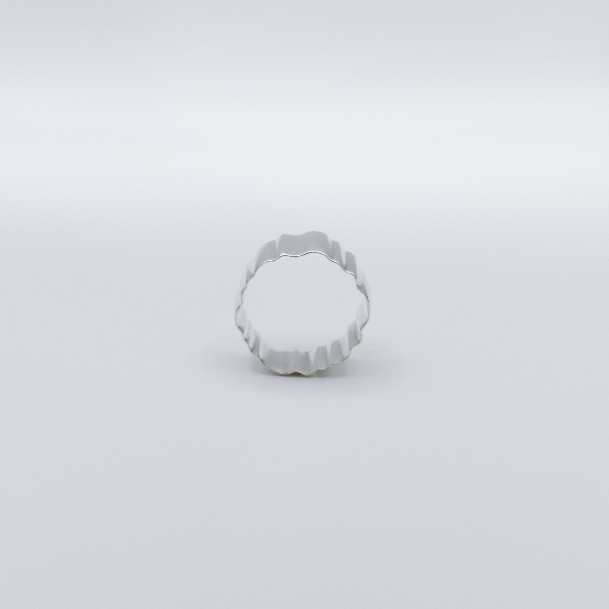 Side view of the Wave silver ring, pictured on a light plain background.