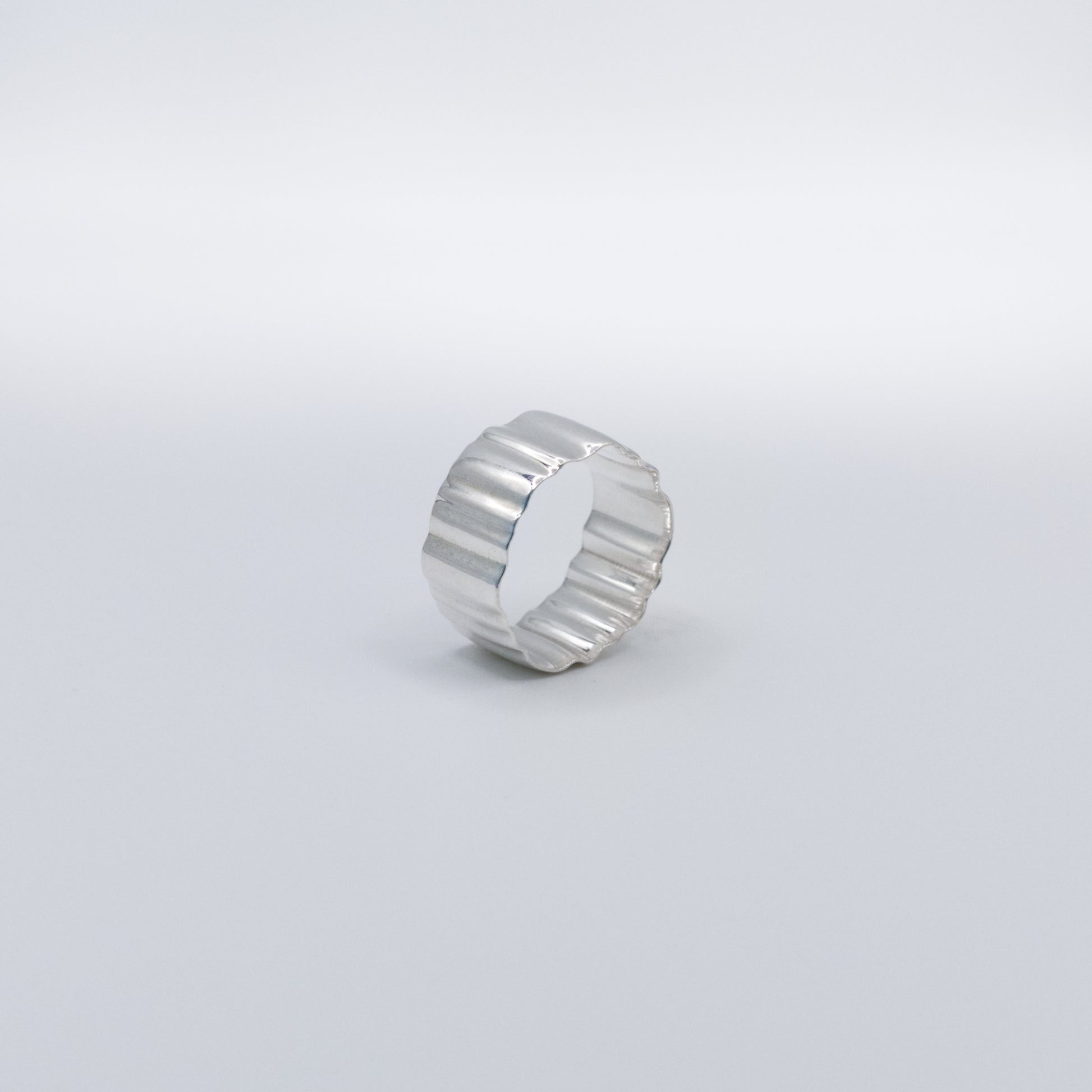 Angled side view of the Wave silver ring, pictured on a light plain background.